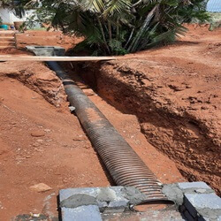 large corrugated pipe being installed in a trench, likely for drainage or water management purposes